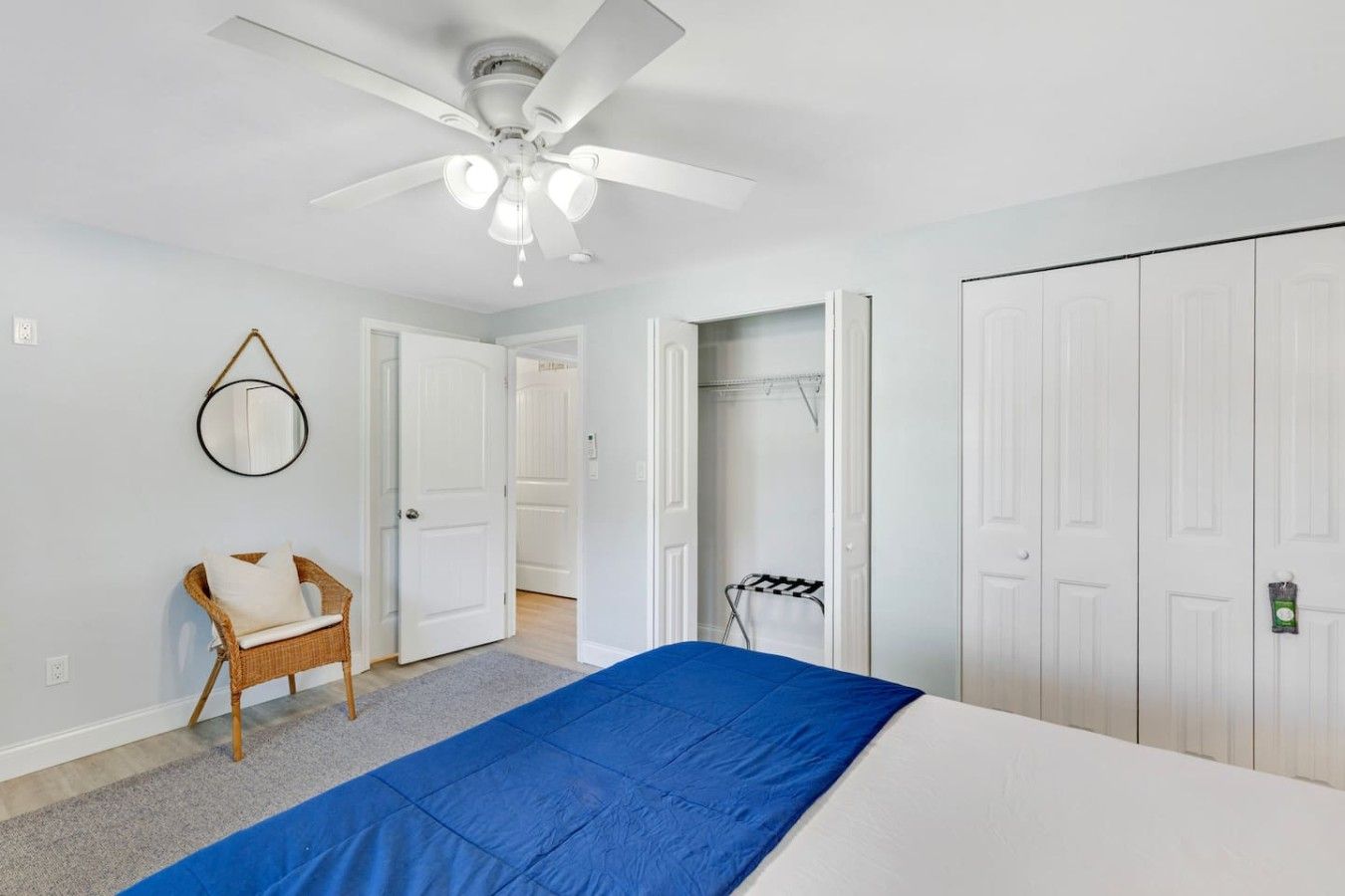 A bedroom with a bed, a ceiling fan, a chair, and a wardrobe.