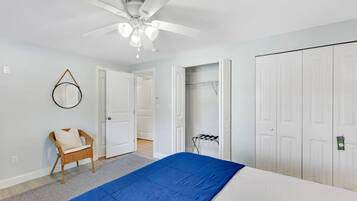 A bedroom with a bed, a ceiling fan, a chair, and a wardrobe.