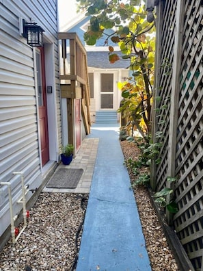 A narrow pathway leading to a house with a wooden deck and a red door. - Downtown Dunedin 917-1/2 (Dunedin)