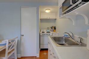 A compact kitchen with white cabinets, a stove, a sink, and a microwave. - Downtown Dunedin 917-1/2 (Dunedin)
