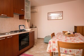 Eine kompakte Küche mit Gaskochfeld, Backofen und einem Essbereich mit Tisch für zwei Personen.