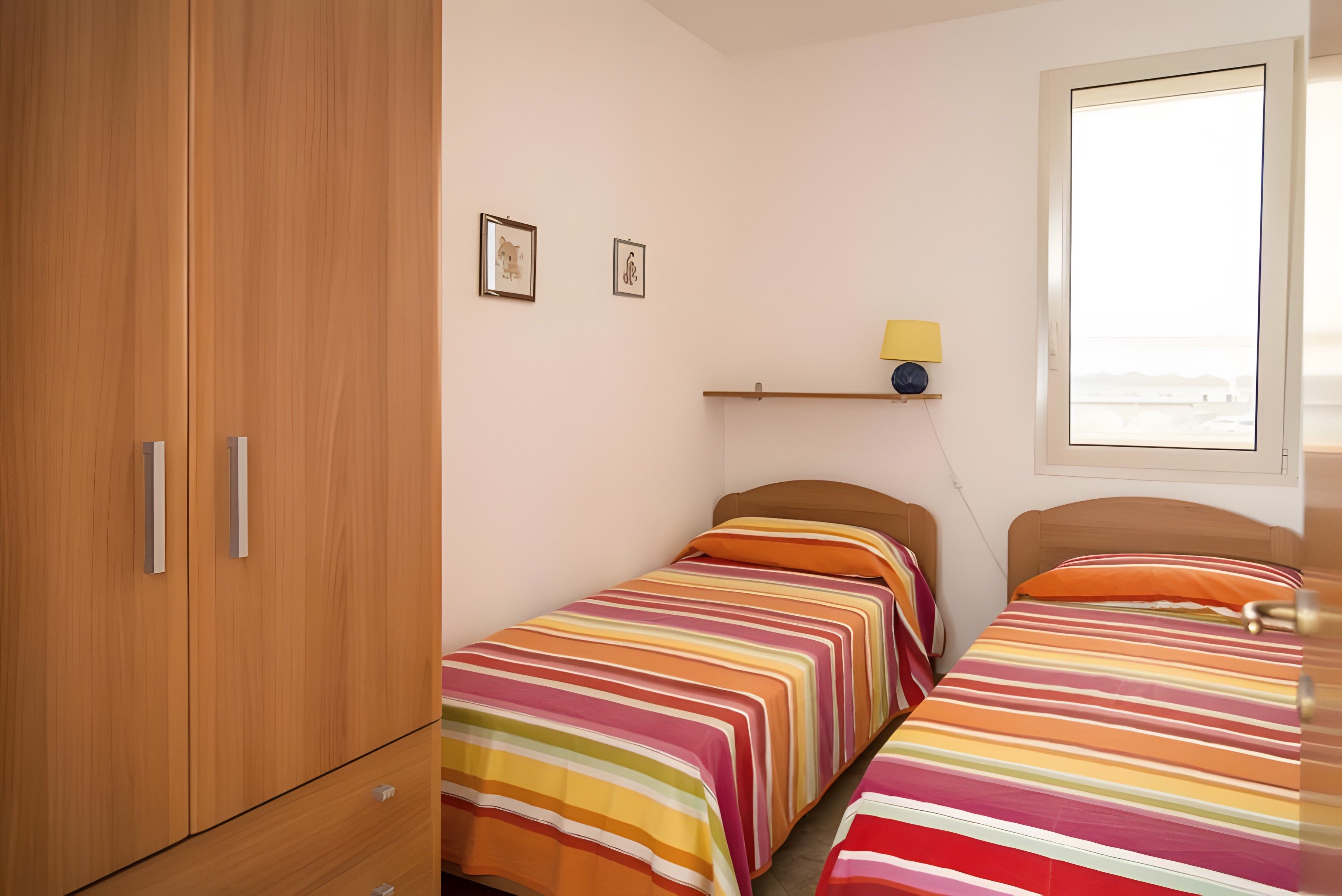 Ein Schlafzimmer mit zwei Einzelbetten, einem Holzschrank und einem Fenster mit Blick.