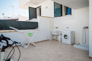 A laundry area with a washing machine, a sink, and a drying rack.