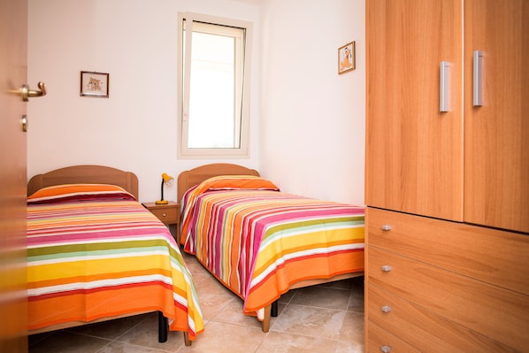 A bedroom with two beds, a wardrobe, and a window.