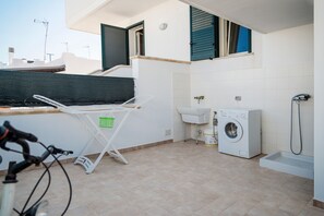 Un espace buanderie comprenant un lave-linge, un évier et un étendoir.