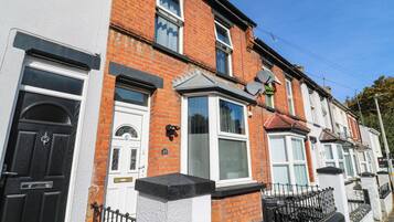 A row of terraced houses with distinct front doors, satellite dishes, and a clear blue sky.