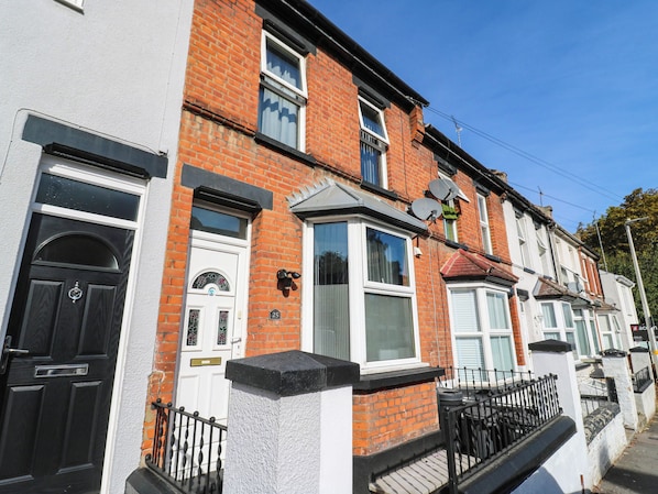 A row of terraced houses with distinct front doors, satellite dishes, and a clear blue sky. - Gillingham House (Gillingham)