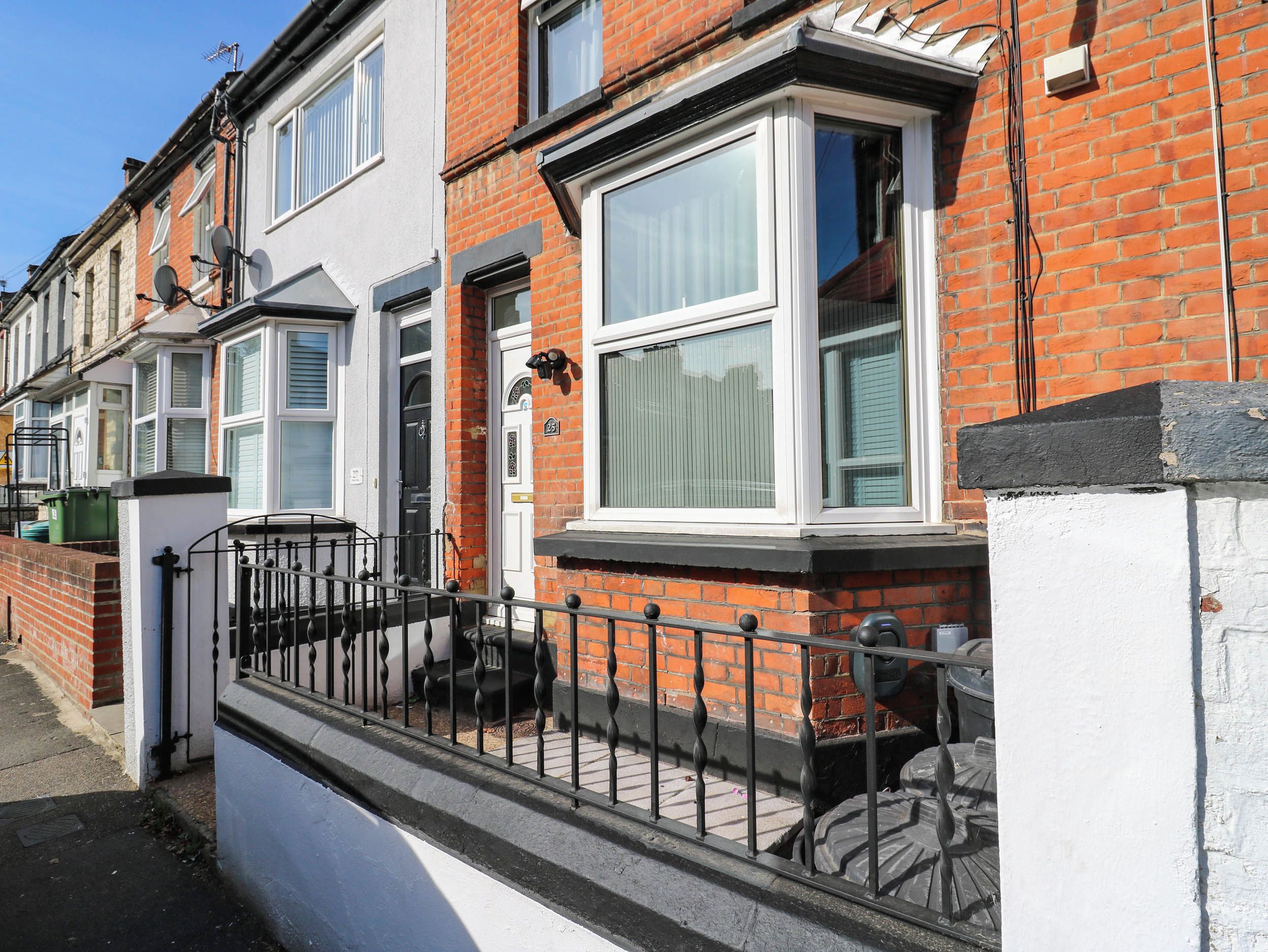 A row of terraced houses with white-framed windows and a black metal fence in front.