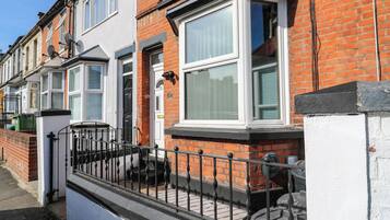 A row of terraced houses with white-framed windows and a black metal fence in front.