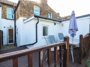 A residential property with a wooden deck, a patio with chairs and an umbrella, and a brick house with a white exterior. - Gillingham House (Gillingham)