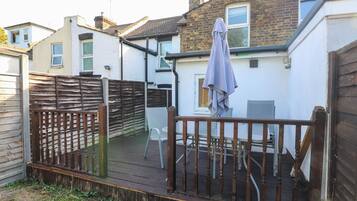 A wooden deck with a railing, a table, and a chair.