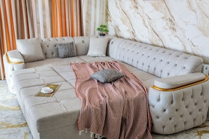 A corner sofa with a patterned throw blanket, a small table with a teacup, and a potted plant. - Apartments Zarafshan city 151 Tashkent (Tashkent)