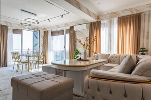 Ein modernes Wohnzimmer mit Marmorboden, einem runden Couchtisch, einer Couch und einem Essbereich mit Stühlen.
