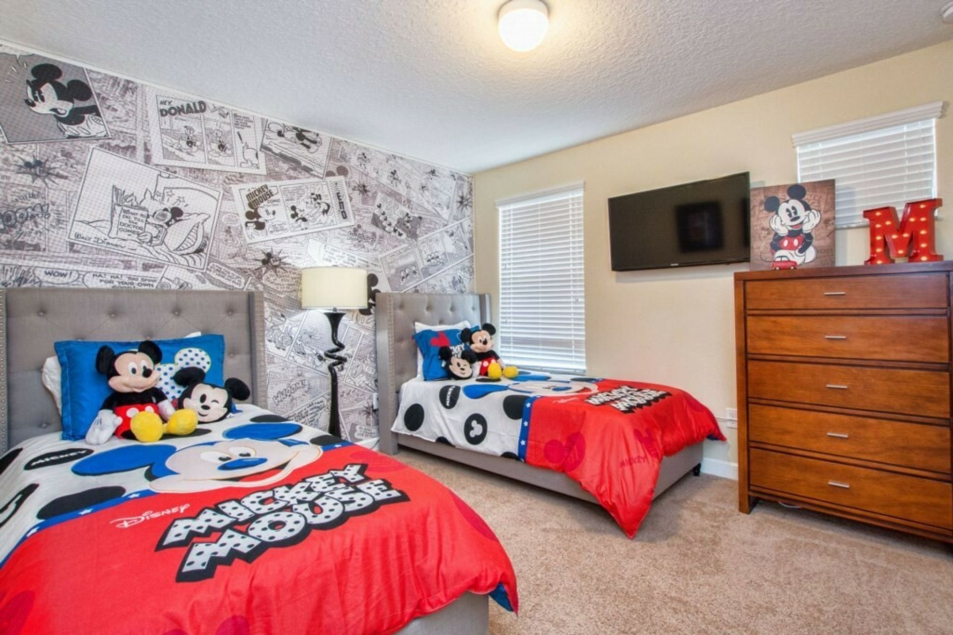 Et soveværelse med to senge, hver pyntet med Mickey Mouse sengetøj.