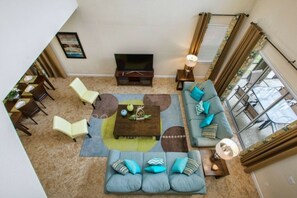 A living room with a sofa, chairs, a coffee table, a TV, and a dining area. - 5BR Home Near Disney Pool & Mickey Room (Kissimmee)