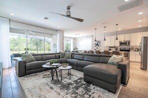 A modern living room with a sectional sofa, two side tables, and a large window. - 6BR Sonoma Resort Home Pool & Cars Game Room (Kissimmee)