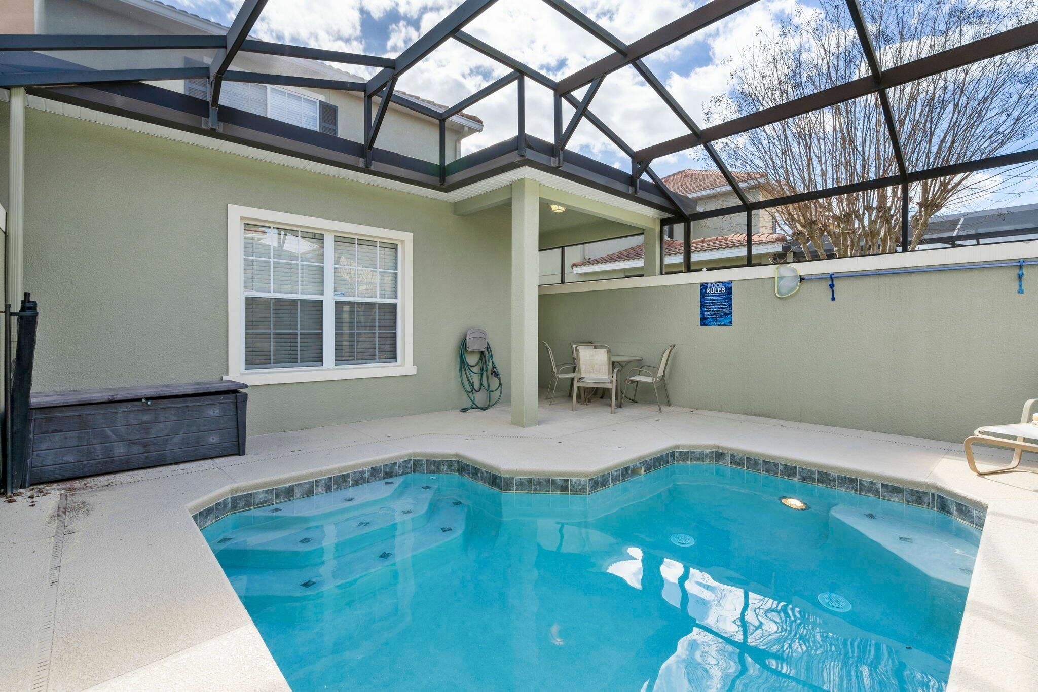 A swimming pool with a glass ceiling, a window, and a chair.