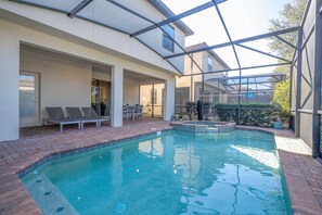 A swimming pool with a glass enclosure, lounge chairs, and a patio area. - 6BR Near Disney Private Pool, Spa, Movie Room (Kissimmee)