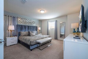 A bedroom with a bed, bedside tables, a bench, a dresser, a mirror, and a television. - 6BR Near Disney Private Pool, Spa, Movie Room (Kissimmee)