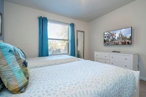 A bedroom with two beds, a television, and a window with curtains. - 6BR Near Disney Private Pool, Spa, Movie Room (Kissimmee)