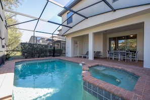 A residential swimming pool with a glass-enclosed patio area, a small deck, and a seating arrangement. - 6BR Near Disney Private Pool, Spa, Movie Room (Kissimmee)