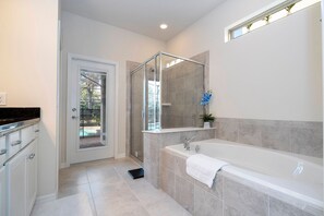 A modern bathroom with a glass shower enclosure, a bathtub, and a sink. - 6BR Near Disney Private Pool, Spa, Movie Room (Kissimmee)
