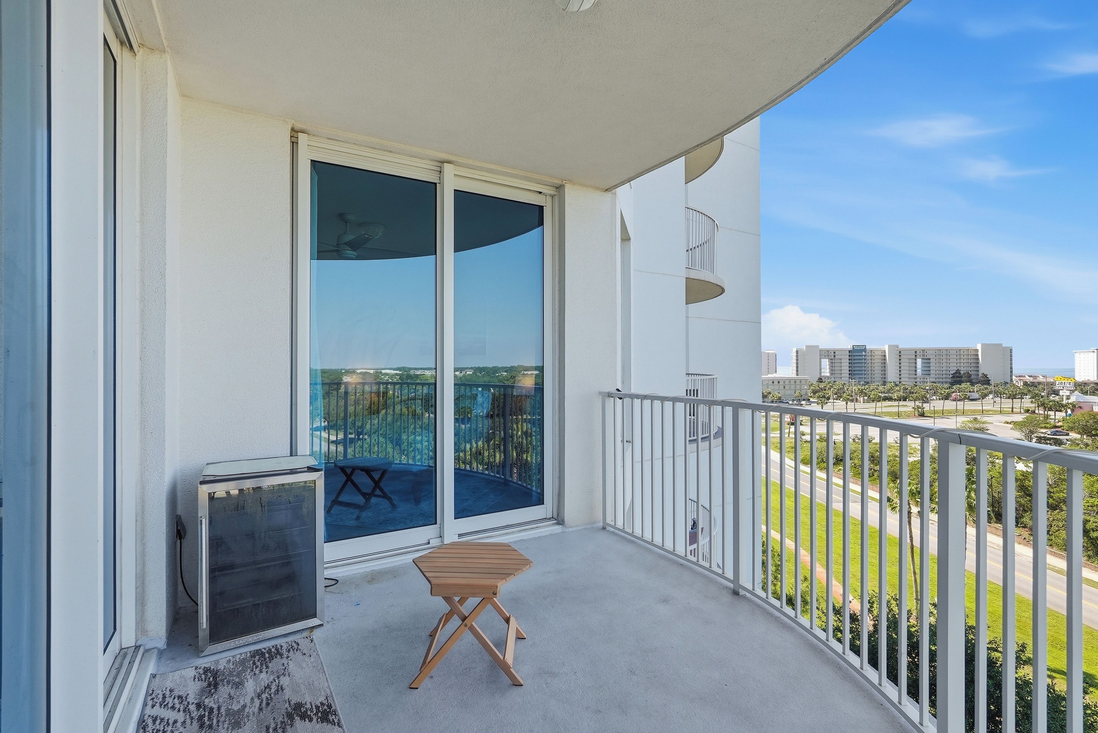 A balcony with a sliding glass door, a small wooden table, and a grill.