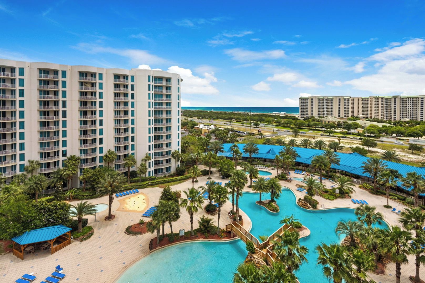 A resort with multiple swimming pools, palm trees, and beachfront views.