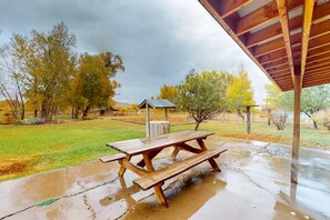 A picnic table under a wooden shelter with a grassy area and trees in the background. - 4BR Home + Apt. w/ Mountain Views, near Wolf Creek (Del Norte)