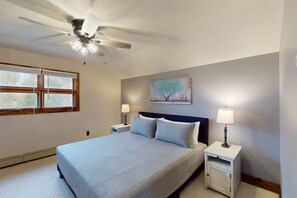 A bedroom with a bed, two bedside tables, a ceiling fan, a window, and a painting on the wall. - 4BR Home + Apt. w/ Mountain Views, near Wolf Creek (Del Norte)