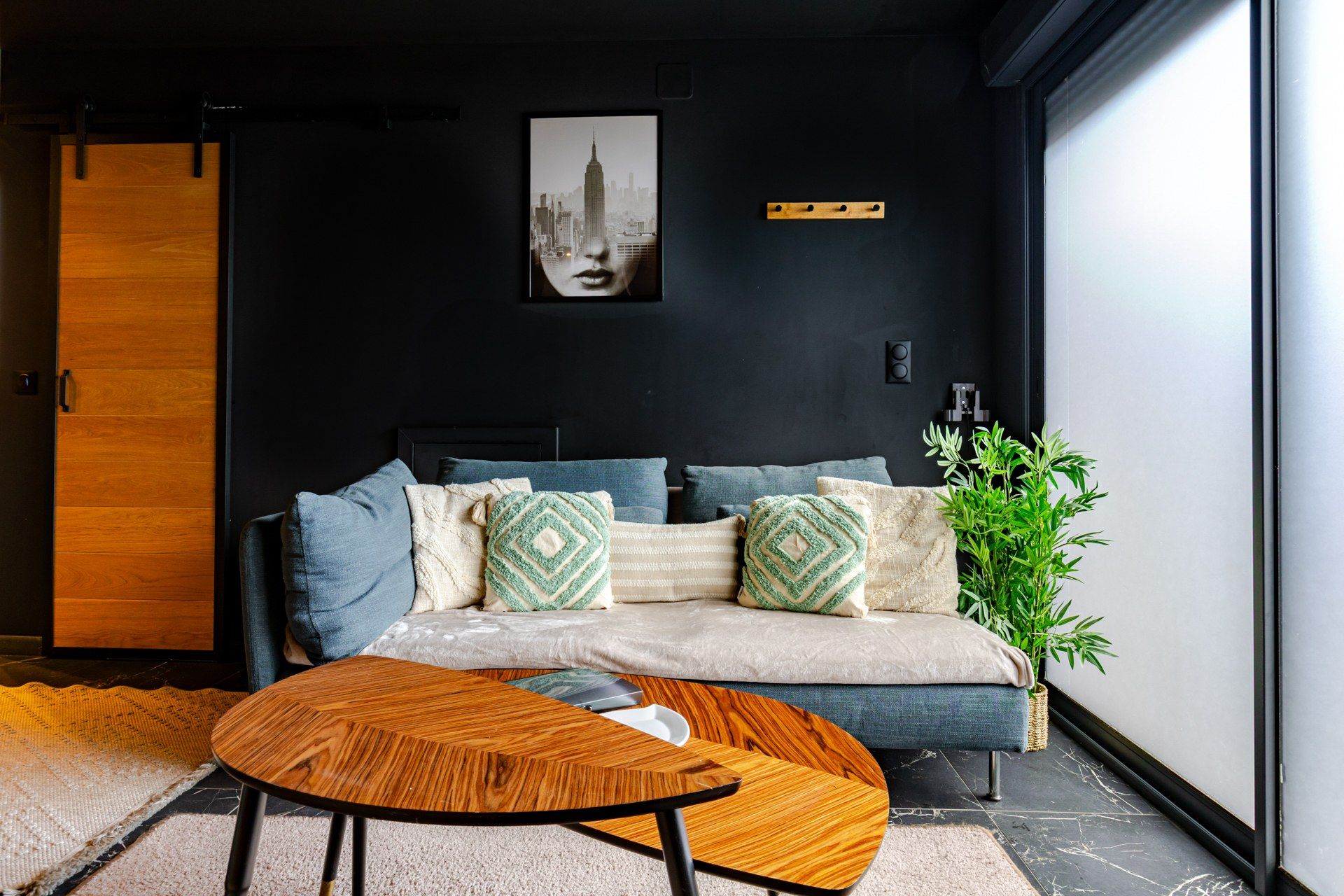 Ein modernes Wohnzimmer mit einer Couch, Kissen, einem Couchtisch und einem Stadtbild an der Wand.