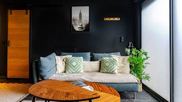 Ein modernes Wohnzimmer mit einer Couch, Kissen, einem Couchtisch und einem Stadtbild an der Wand.