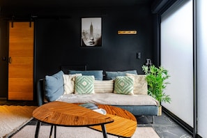 A modern living room with a sofa, pillows, a coffee table, and a cityscape artwork on the wall.