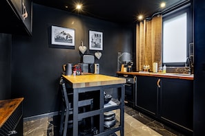 Una cocina compacta con una mesa de madera, armarios negros y una ventana con cortinas.