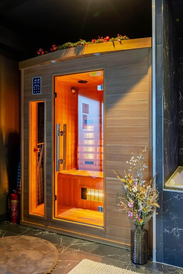 A sauna with a wooden exterior, a digital control panel, and a visible interior with a bench and a window.