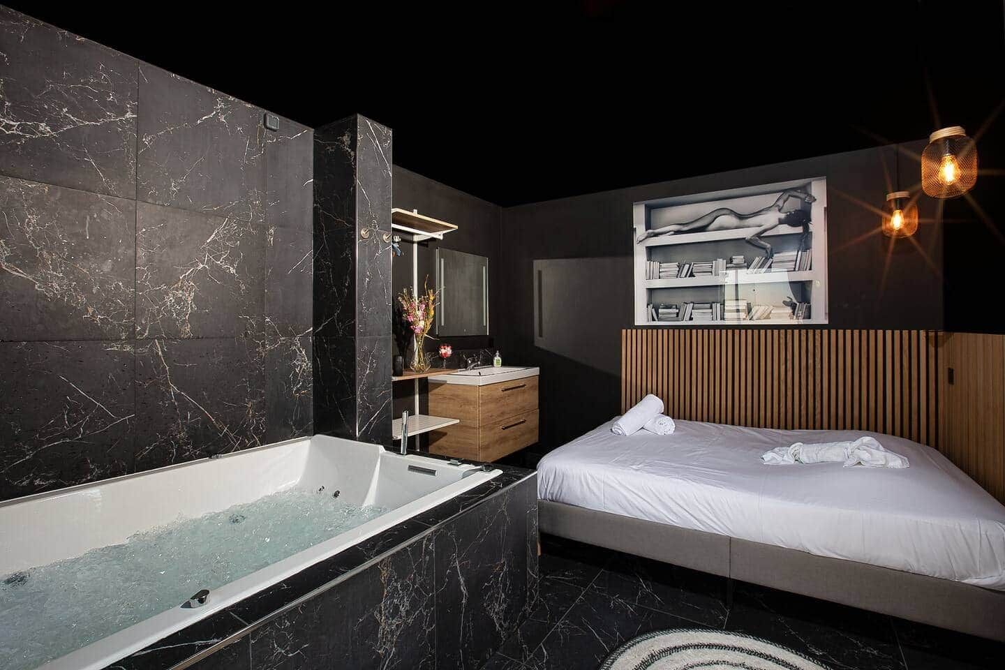 Ein modernes Badezimmer mit Marmorwand, einer Badewanne, einem Holzwaschtisch und einem Bett mit Kopfteil.