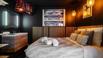 A modern bedroom with a large bed, a bedside table, a mirror, a TV, and a bookshelf.