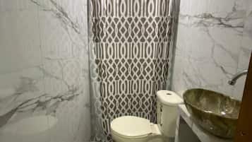 A bathroom with a toilet, a sink with a large basin, and a shower curtain with a geometric pattern.