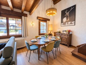 A dining area with a wooden table, chairs, and a chandelier. - Peaceful family chalet - 6 guests (Les Gets)