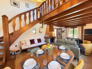 A dining area with a wooden staircase, a stone fireplace, and a cozy seating arrangement. - Peaceful family chalet - 6 guests (Les Gets)