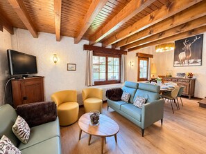 A cozy living room with a sofa, chairs, a coffee table, and a television. - Peaceful family chalet - 6 guests (Les Gets)