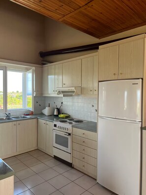 A kitchen with light-colored cabinets, a stove, oven, and a refrigerator. - The sea view house of Xenia and Panos by MPS (Paralia Avlidos)