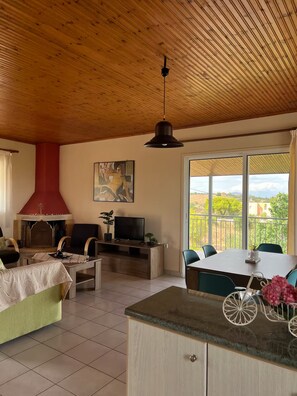A spacious living area with a wooden ceiling, a fireplace, a television, and a dining table with chairs. - The sea view house of Xenia and Panos by MPS (Paralia Avlidos)