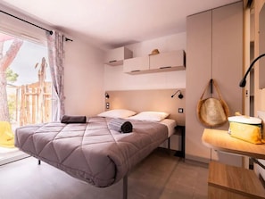 Ein modernes Schlafzimmer mit einem Bett, Nachttischen und Blick ins Freie.