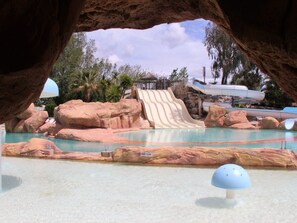 Un parc aquatique doté d’un grand toboggan, d’une piscine et de formations rocheuses.