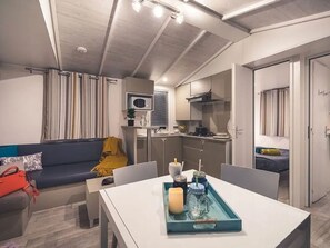 A compact living space with a kitchenette, a dining area, and a sofa. - Air-conditioned mobile home - 6 guests (Agde)