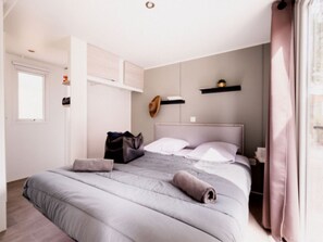 A bedroom with a bed, a nightstand, a wall-mounted shelf, and a door. - Mobile home, jacuzzi, AC - 6 guests (Agde)