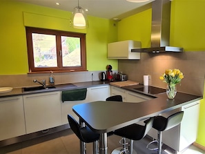 A modern kitchen with a central island, bar stools, a window with a view, and a vase with flowers. - Mountain lodge, Vosges view (Goldbach-Altenbach)