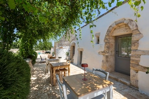 A rustic outdoor seating area with stone walls and a wooden table. - Masseria Le Monache by Perle di Puglia (Martina Franca)