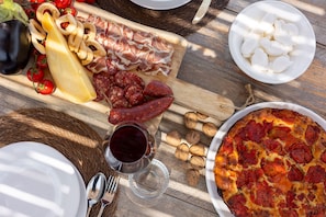 A wooden table with a variety of food items including cheese, cured meats, and a pizza. - Masseria Le Monache by Perle di Puglia (Martina Franca)